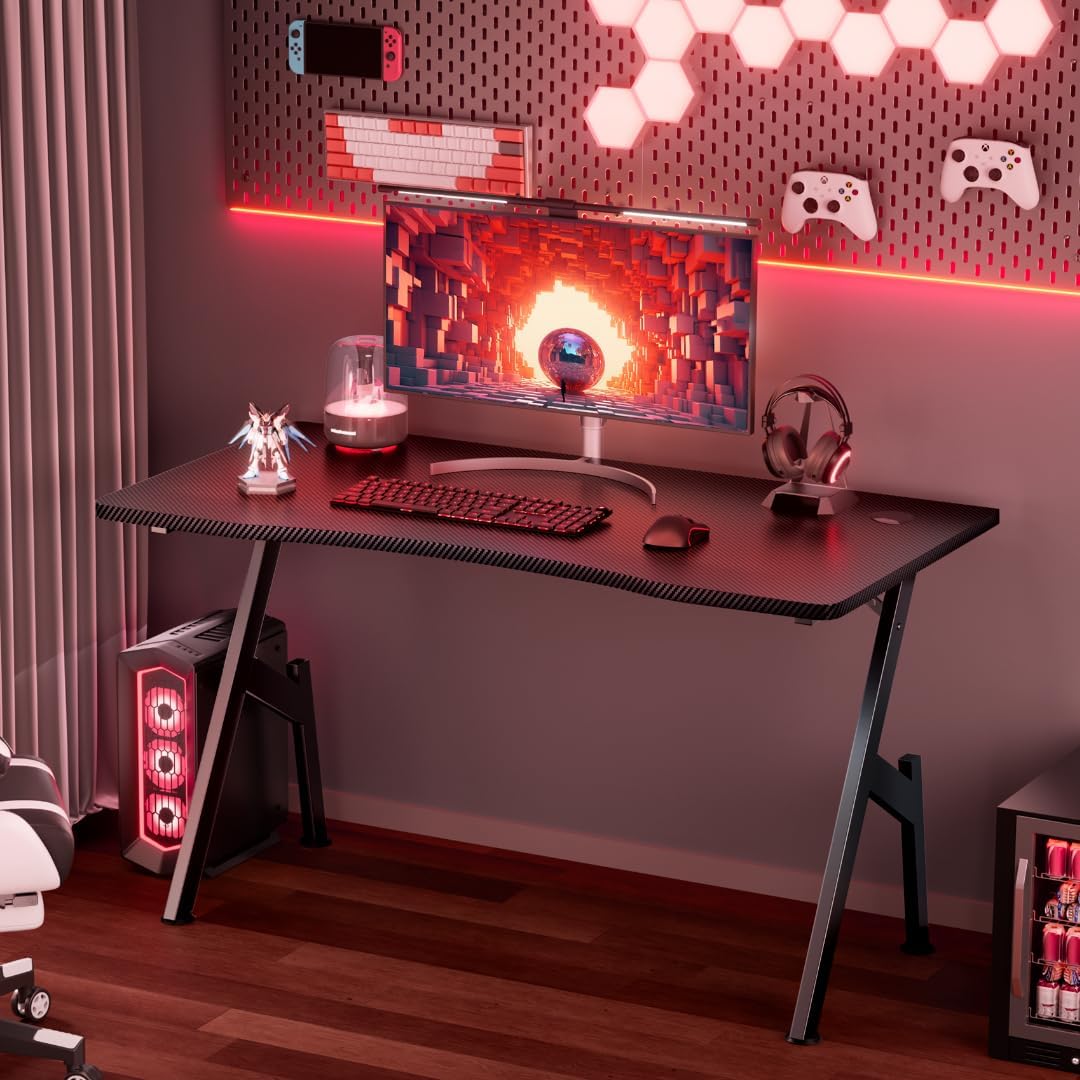Ergonomic gaming desk with red ambient lighting, single curved monitor, and carbon fiber texture in a cozy gaming room